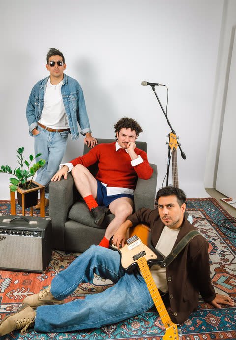 Los tres integrantes en un living con sillón, alfombra y amplificador